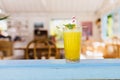 Blur photo of cafe with glass of orange juice in focus. Picture of sweet cold cocktail with mint