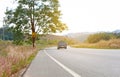 Blur photo of a landscape of curve long asphalt road and car traveling to the mountain in beautiful nature, a big tree on the left