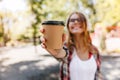 Blur portrait of adorable woman holding cup of coffee. Carefree stylish girl enjoying summer day. Royalty Free Stock Photo
