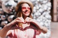 Blur portrait of smiling debonair girl expressing love. Outdoor shot of magnificent lady making hea