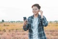 Blur soft-focus smiling Asian young man listening to the podcast is a music audio mp3 player on smartphone outdoors nature sunset