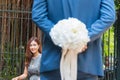 White bouquet flowers of the handsome man behind his back. Focus girl sitting happy smile