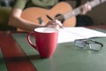 Blur woman musician with guitar writing on book at desk