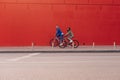 Blurred abstract photo, focus on the asphalt on the background of a couple of cyclists riding near a red wall. Copy space