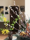 Blurred background of bouquet of willow branches with blossoming willow buds and spring flowers on table. Happy easter