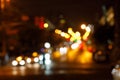 The blurred background of bright dipped headlamps with the illuminated night city landscape behind.