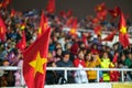 Blurred background of crowd of Vietnamese football fans at My Dinh stadium. Supporter with red clothes raising flags.