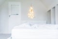 Blurred background of glowing lights Christmas tree on the white wall above the bed in the bedroom. Simple, minimal conscientious