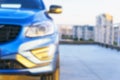 Blurred background with modern luxury car on the blur roof of the building. Modern car exterior details. Soft lightning.