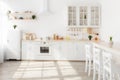 Blurred background of modern sunny kitchen. White kitchen furniture with utensils, plants in pots on shelves Royalty Free Stock Photo