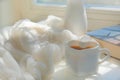 Blurred background of morning still life, coffee in bed. White cup in shape heart and fluffy scarf. Shadow and sunlight. At home. Royalty Free Stock Photo