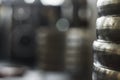 Blurred background picture of gym equipment with sharp stack of old scratched weight plates in front