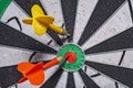 Blurred background in soft focus with a darts board with a closeup of an arrow hitting the center and an opponent`s arrow stuck ne