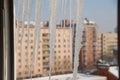 Blurred background of a winter cityscape with apartment buildings in snow. Few of icicles in the foreground in defocus.