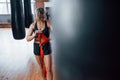 Blurred black pushing bag on the right side. Getting prepared for boxing workout in the gym. Adult blonde woman