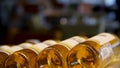 Blurred bottles of white and rose wine are nicely laid out in a row on a shelf in a large supermarket. Bright abstract