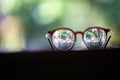 Blurred brown eyeglasses with on wooden table, In bokeh green garden background, Close up & Macro shot, Selective focus, Optical