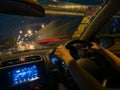 Blurred car driver view seeing a woman hand driving during the rain at night. Outside have a motion blur truck passing by