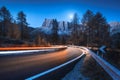 Blurred car headlights on winding road at night in autumn