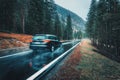 Blurred car in motion on the road in autumn forest in rain Royalty Free Stock Photo