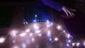 Blurred Christmas string lights and kid hands touch glittering craft papers for making craft projects at holiday