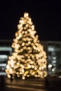 Blurred Christmas tree silhouette illuminated and decorated with golden lights