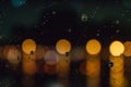 Blurred city lights with rain drops foreground. Unfocused colorful lights behind glass with drops. Shiny lights of night bokeh. Royalty Free Stock Photo