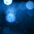 Blurred city lights with rain drops foreground. Unfocused colorful lights behind glass with drops. Shiny lights of night bokeh Royalty Free Stock Photo