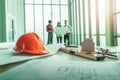 Blurred contractor team brainstorming at the far end of home developer desk with constructoion tools with light flare from the