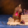 Ramadan concept. Stillife with a Ramadan Lantern and box with dates. Dark blue wooden table.