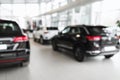Blurred dealership store interior with brand new luxury cars, copy space