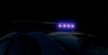 Blurred defocused silhouette of road police patrol car on the street of city at night. Flashing blue police car led lights in Royalty Free Stock Photo