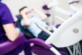 Blurred dental office. Tools are in the foreground. A boy with goggles in the dental chair