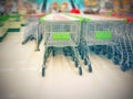 Blurred empty shopping carts green and white handles in a large supermarket; Royalty Free Stock Photo