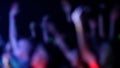 Blurred Fans Raise Hands and takes a photos in Front of Bright Colorful Strobing Lights on Stage.