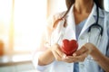 Blurred female doctor with stethoscope holding heart. This picture is focus at female doctor hand and use warm bright sunlight