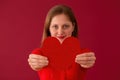 Blurred female showing heart to the camera on red background