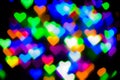 Blurred festive background with defocused colourful glitter formed a heart, bokeh in a shape of a heart. Original photographic