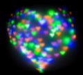 Blurred festive background with defocused colourful glitter formed a heart, bokeh in a shape of a heart. Original photographic