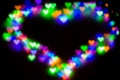 Blurred festive background with defocused colourful glitter formed a heart, bokeh in a shape of a heart. Original photographic