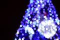 Blurred fragment of the New Year tree. Lots of round lights in blue