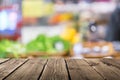 Blurred fresh herbs counter at market with empty rustic wooden planks on the foreground. Can be used for advertise products.