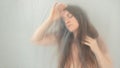 Blurred, fuzzy image of sensual dreamy portrait of a young long haired woman in her dream world behind plastic foil