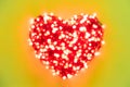 Blurred garland with red lights folded in the shape of a heart on a yellow background Royalty Free Stock Photo