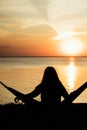 Blurred girl sitting on a hammock in a pine forest on the edge of a cliff near the sea and watching the sunrise Royalty Free Stock Photo