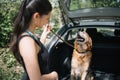 Blurred girl standing in front of opened trunk with dog