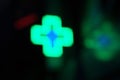 Blurred Glowing neon green medical cross sign on a black background, night Royalty Free Stock Photo