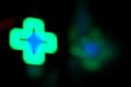 Blurred Glowing neon green medical cross sign on a black background, night Royalty Free Stock Photo