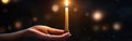 Blurred hand igniting candle with shining flame, symbolizing hope and light amid blurry lights Royalty Free Stock Photo