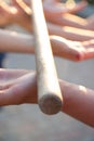 Blurred hands hold a blurred, wooden stick. teambuilding activity with a stick and hands. colleagues. rays of the sun fall, light